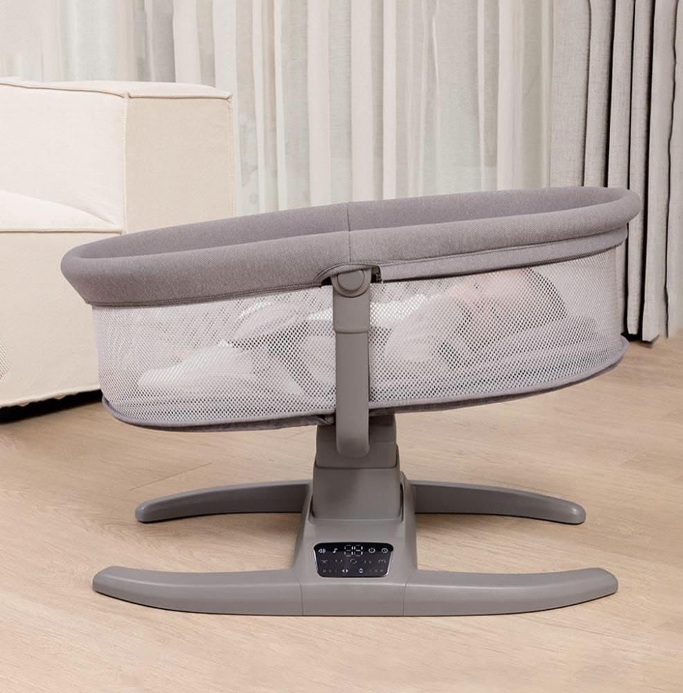 Gray baby bassinet on a wooden floor with a neutral background