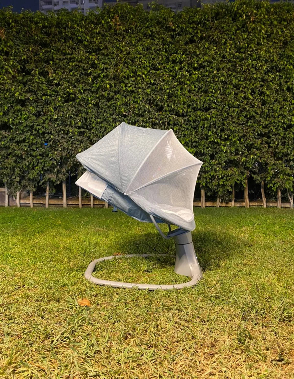 Chair with a white cover on grass in front of a hedge