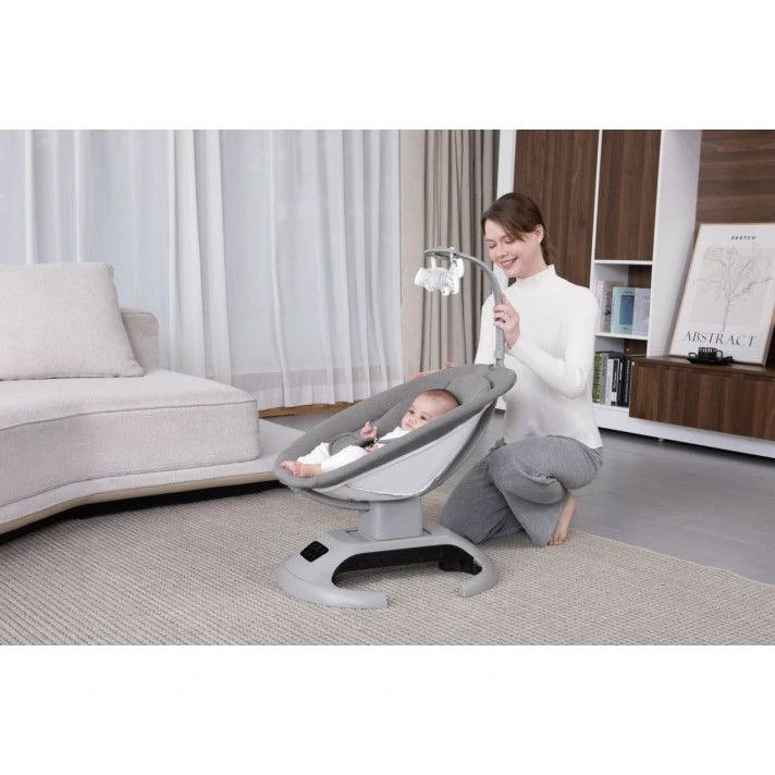 Woman with a baby in a gray baby swing in a living room.