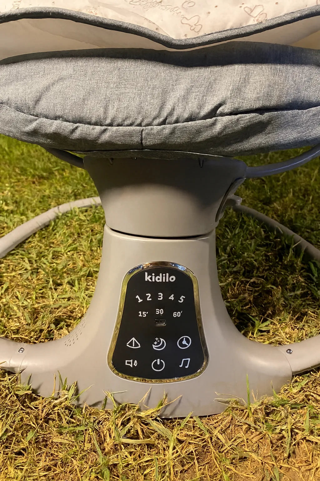 Gray baby bouncer with digital display on a grassy surface